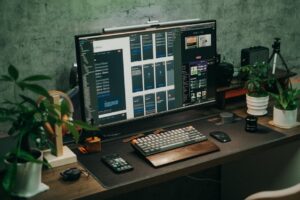 A tidy office desk featuring a computer monitor, keyboard, and plants for a modern workspace vibe.
