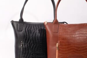 Stylish black and brown leather handbags with crocodile texture on a white background.