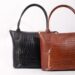 Stylish black and brown leather handbags with crocodile texture on a white background.