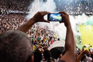 Thrilling football match scene with fans capturing the moment on a smartphone from the stadium stands.
