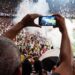 Thrilling football match scene with fans capturing the moment on a smartphone from the stadium stands.